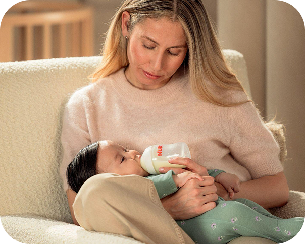 Mother feeding baby with NUK bottle
